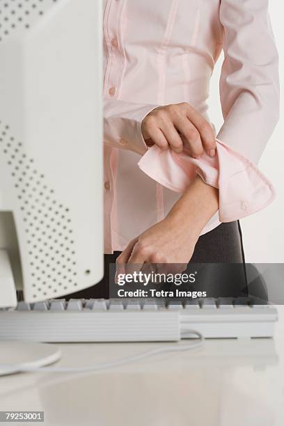 woman rolling up sleeves at computer - sleeve roll stock pictures, royalty-free photos & images