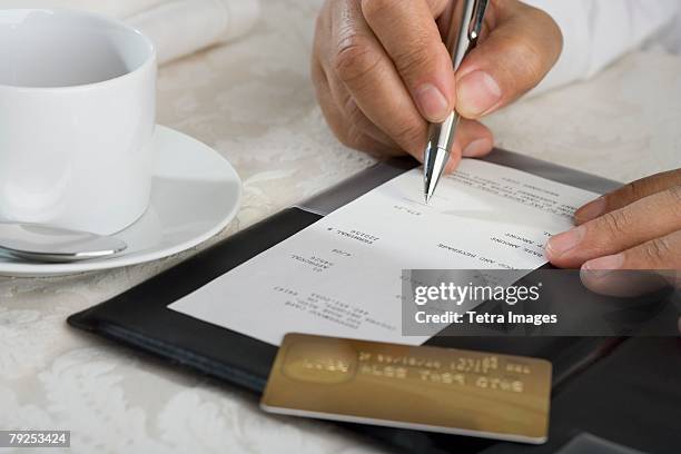 close up of man signing credit card receipt at restaurant - gratuity stock pictures, royalty-free photos & images