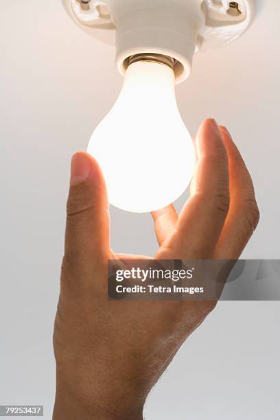 close up of lightbulb being screwed in - hände glühlampe stock-fotos und bilder