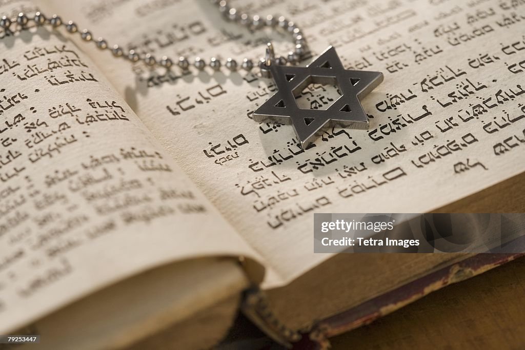 Star of David necklace on book with Hebrew text