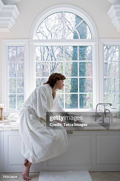 woman in robe drawing bath - gewaad stockfoto's en -beelden