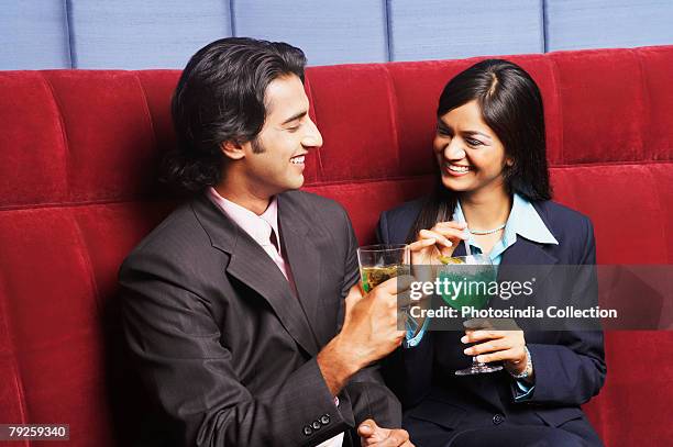 close-up of a businesswoman and a businessman sitting on a couch and holding glasses - rietje los stockfoto's en -beelden