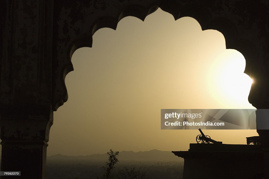 "Silhouette of a cannon viewed through an arch at sunset, Neemrana Fort, Neemrana, Alwar, Rajasthan, India"