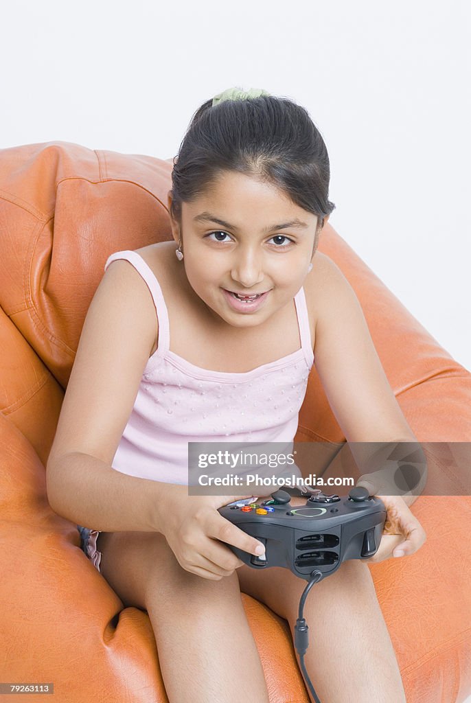 Portrait of a girl sitting on a bean bag and playing a video game