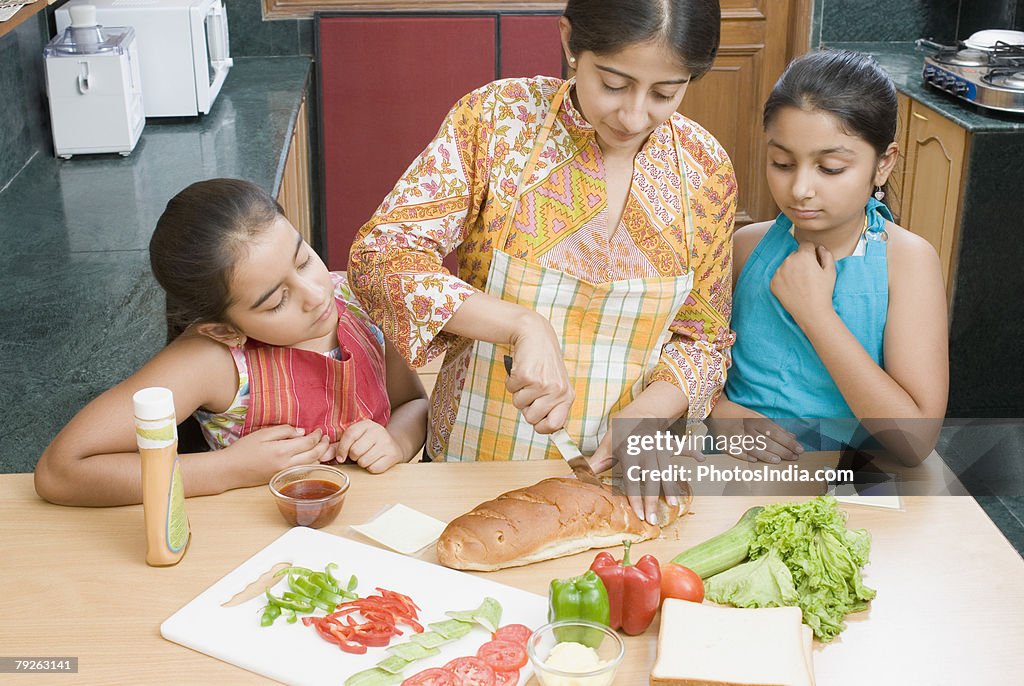 Close-up of a mid adult woman making sandwiches with her daughters