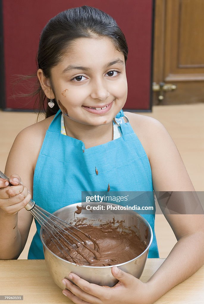 Portrait of a girl stirring chocolate sauce with an egg beater