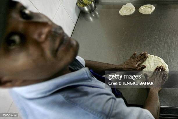 An Indian migrant restaurant worker prepares a flatbread called roti canai, a local breakfast staple, at a restaurant in Kuala Lumpur, 26 January...