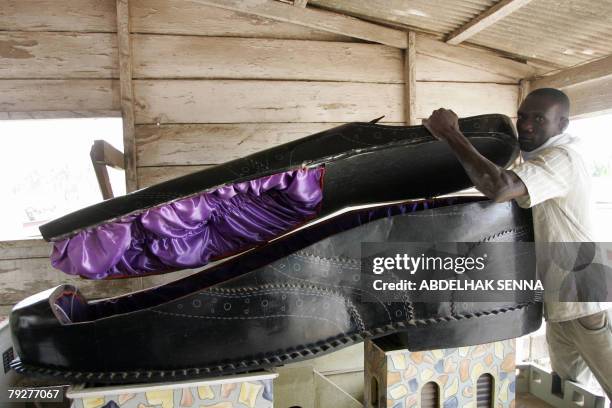 Ghanean undertaker opens a coffin, shaped like a shoe, in his showroom in Accra 27 January 2008. Customized coffins are popular in Ghana and can...