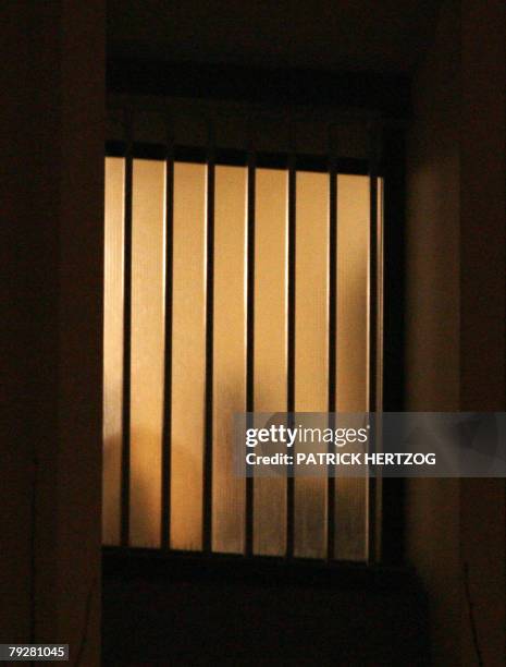 The shadow of an unidentified man is seen through the window of the headquarters of the Paris police's financial brigade, 27 January 2008, where...