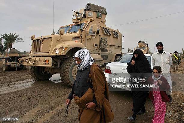 Iraqis walk past Mine Resistant Ambush Protected armoured vehicles of the US army's 1-15 Infantry of 3rd Infantry Division in Al-Jara, on the...