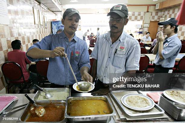 Migrant restaurant workers dish out sauces to be eaten with a flatbread called roti canai, a local breakfast staple, at a restaurant in Kuala Lumpur,...