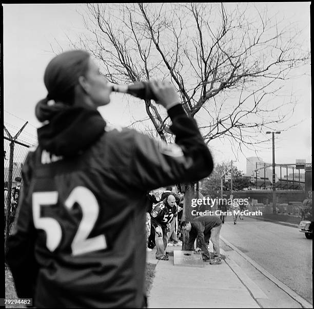 Woman drinks a beer while waiting to play a tailgating game prior to the start of the AFC Divisional Playoff game between the Baltimore Ravens and...