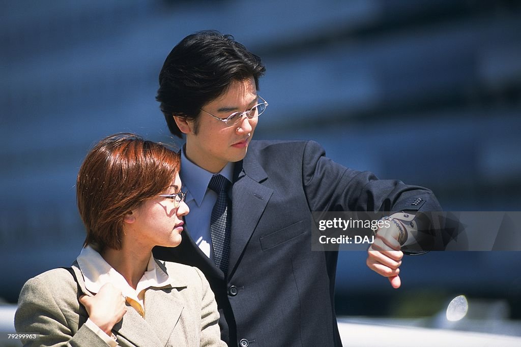 Portrait of businessman and businesswoman looking at watch, Pin Focus