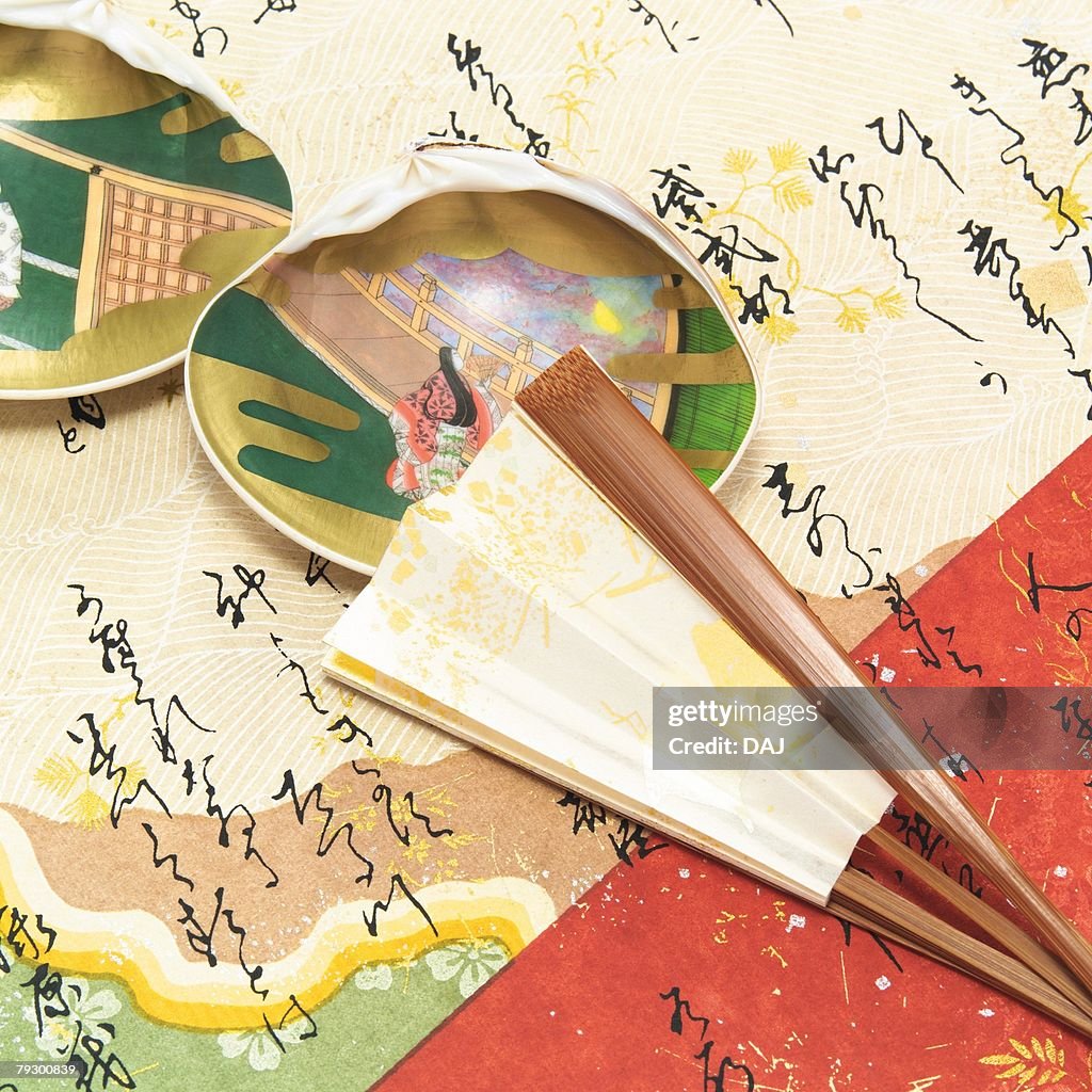 Painted clamshells and Japanese folding fan on paper written Japanese poem, high angle view