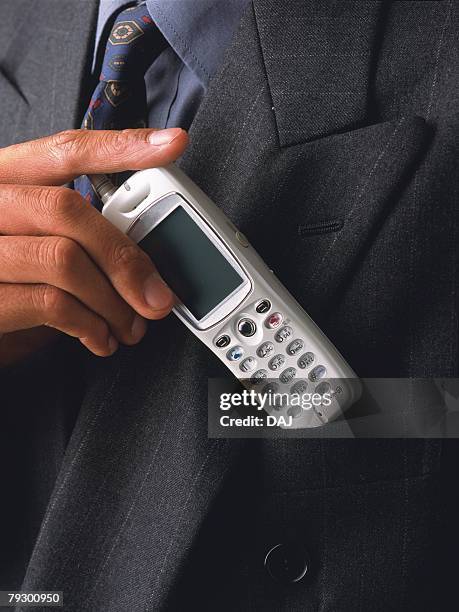 businessman putting mobile phone into pocket, front view, close up - silver putter stock pictures, royalty-free photos & images