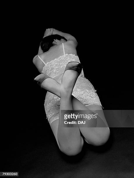 photography of a woman lying face down with crossed legs, high angle view, black and white - black stockings suspenders adult fotografías e imágenes de stock