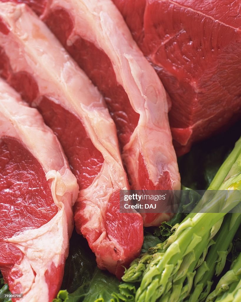 Raw beef steaks with asparagus, high angle view, close up