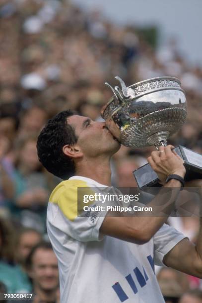 Tennis player Andres Gomez kisses the trophy he has just received after winning the French Open against Andre Agassi.