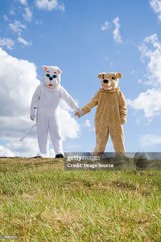 People in cat and dog costumes holding hands