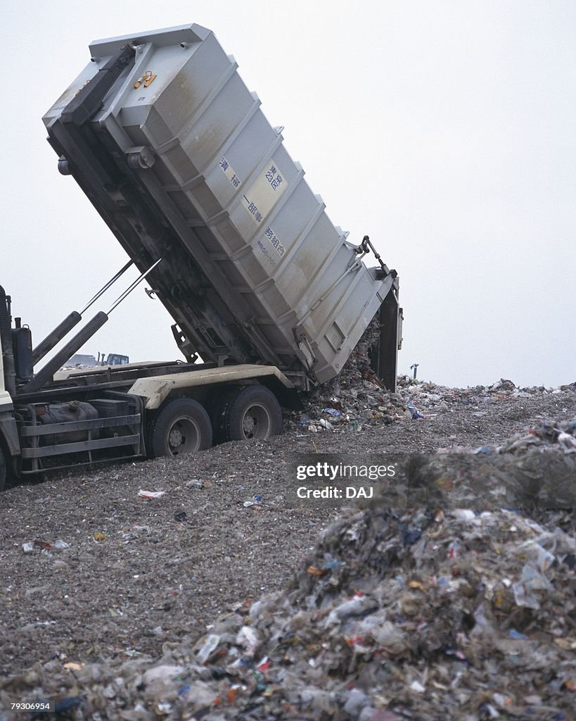 Bulldozer spreading trash in landfill, low angle view