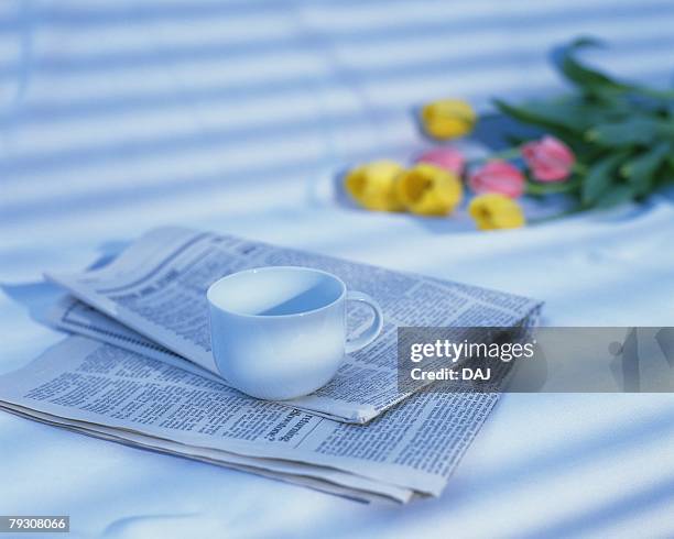 cup on newspaper and floers, close up, high angle view, differential focus, toned image - newspaper on table ストックフォトと画像