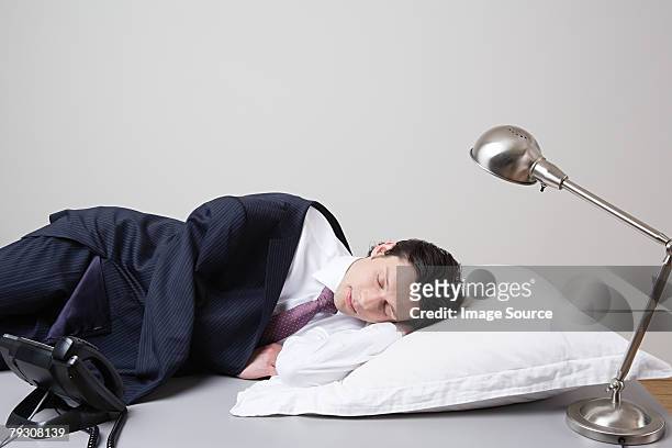 uomo d'affari che dorme sulla scrivania - angle poise lamp foto e immagini stock