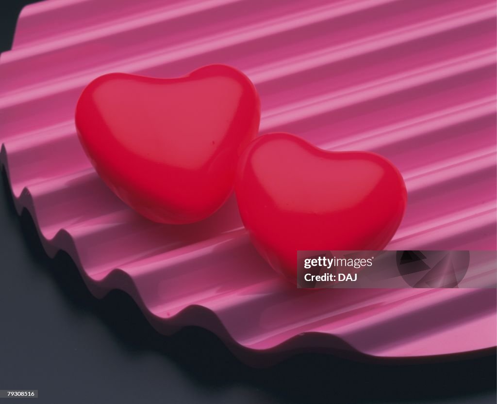 Two red hearts on corrugated plate, high angle view, close up, black background