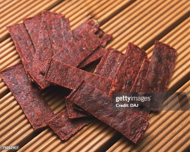 closed up image of several slices of beef jerky on a wooden surface, high angle view - beef jerky stock-fotos und bilder