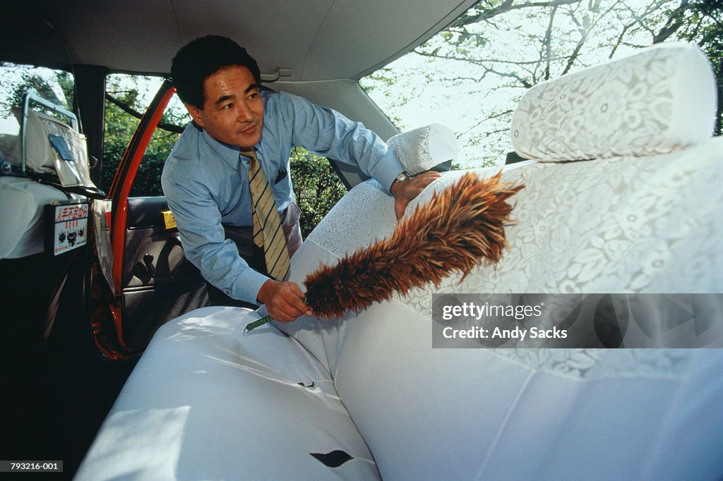 Japan,Tokyo,taxi driver dusting interior of cab