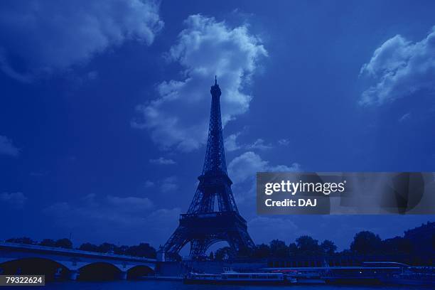 image of the eiffel tower under a deep blue sky and some clouds, low angle view, paris, france - eiffel tower at night stock pictures, royalty-free photos & images