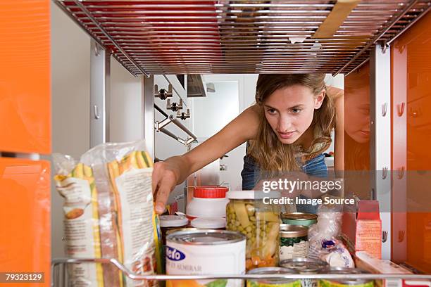 a woman reaching for a packet of food - cabinet bildbanksfoton och bilder