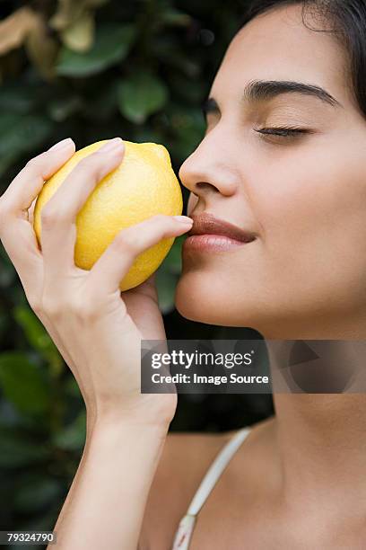 woman smelling a lemon - agrumi foto e immagini stock