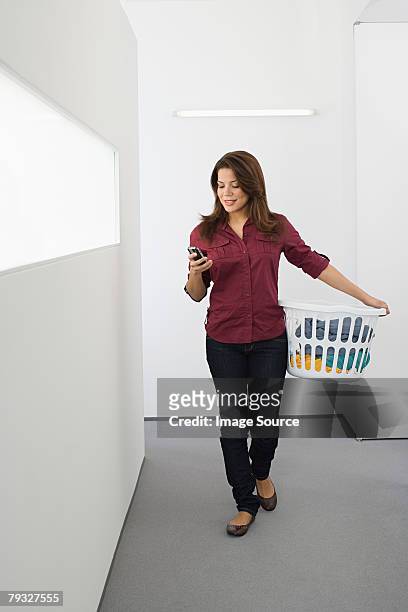 woman text messaging and doing the laundry - laundry basket imagens e fotografias de stock