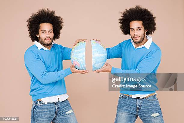 twins holding two halves of the earth - identical twins stockfoto's en -beelden