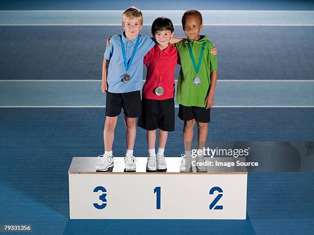 boys on winners podium - medal podium stock pictures, royalty-free photos & images