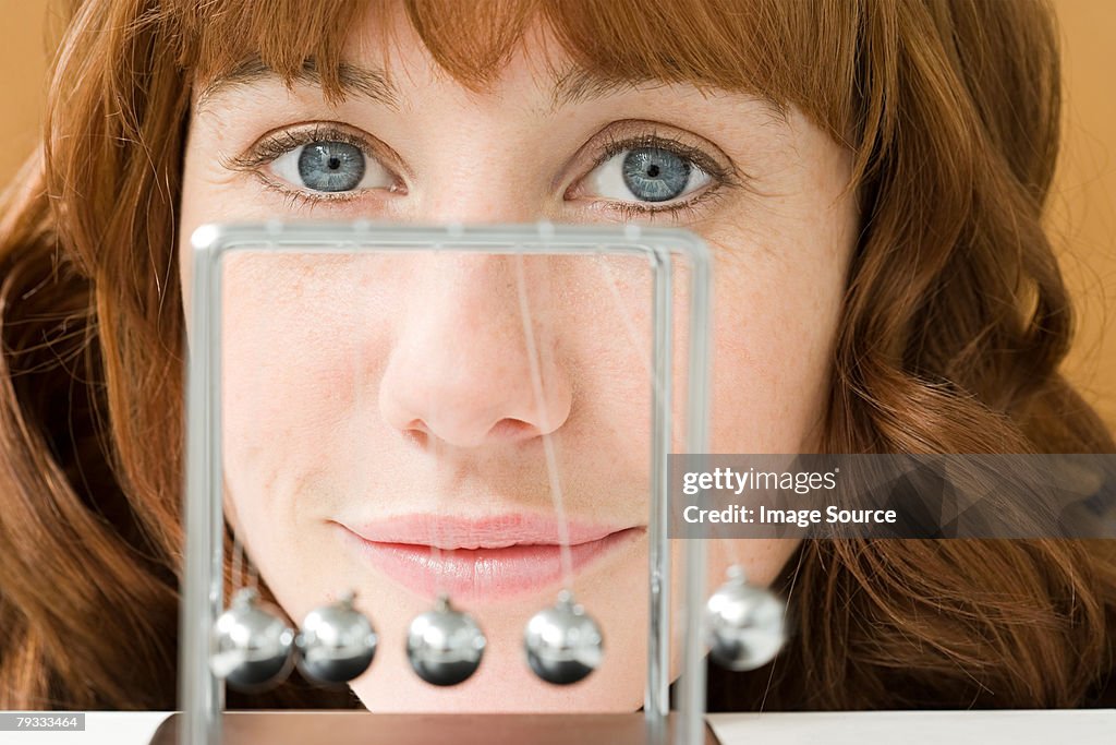 A woman and a newtons cradle