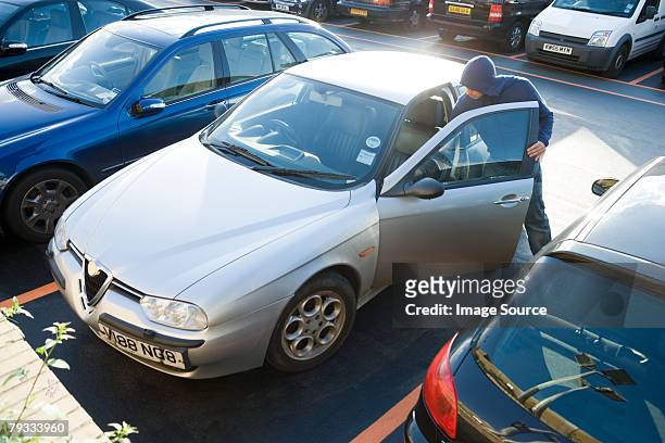 a thief breaking into a car - car theft stock pictures, royalty-free photos & images