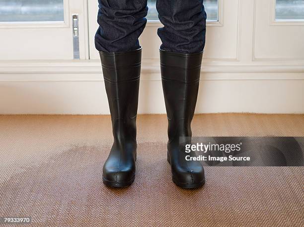 person wearing rubber boots on a wet carpet - wet carpet stock pictures, royalty-free photos & images