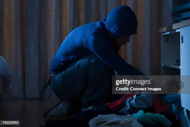 burglar looking through cupboard - haus einbruch stock-fotos und bilder