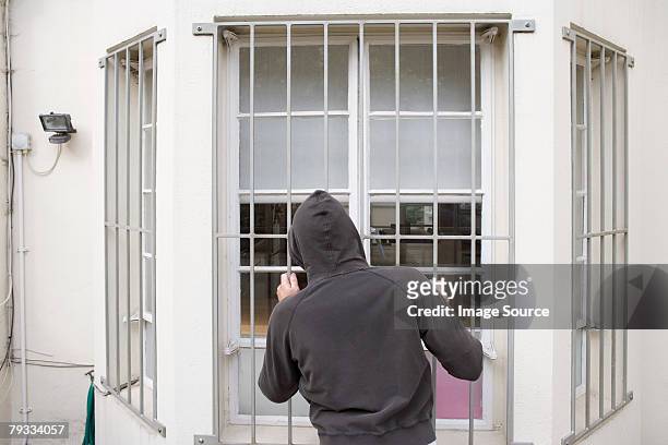 a thief looking through a window - security screen stock pictures, royalty-free photos & images