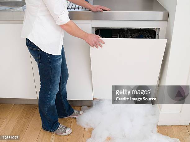 woman opening a leaking dishwasher - broken appliance stock-fotos und bilder