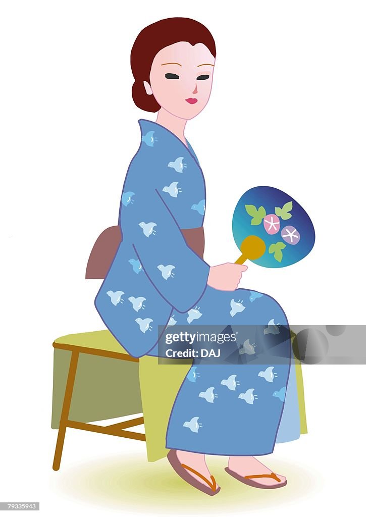 Woman sitting and holding paper fans in Japanese style clothing, side view, Japan