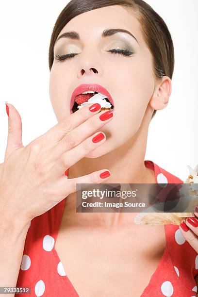 woman enjoying eating a cake - greed stockfoto's en -beelden