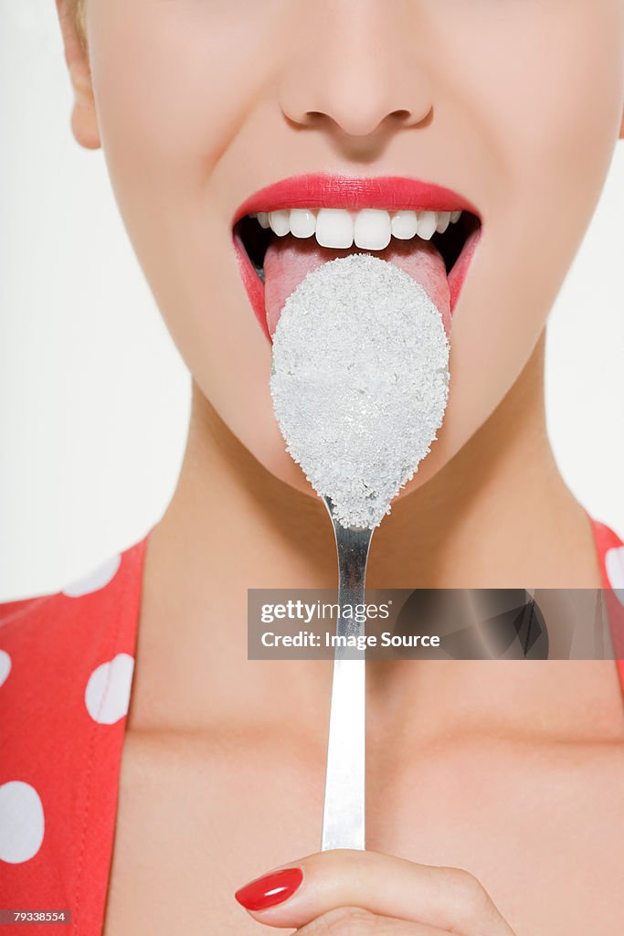 Woman licking a sugary spoon