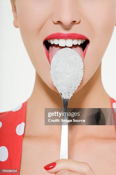 woman licking a sugary spoon - sugar cube stock pictures, royalty-free photos & images