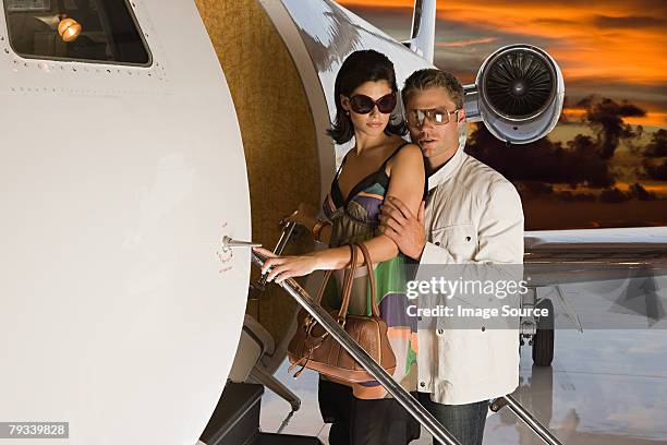 glamouröses paar boarding jet - alles hinter sich lassen stock-fotos und bilder