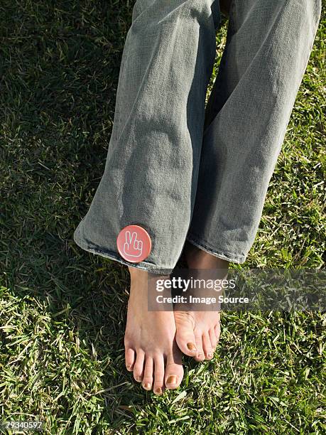 woman wearing a peace badge - jeans barefoot stock pictures, royalty-free photos & images