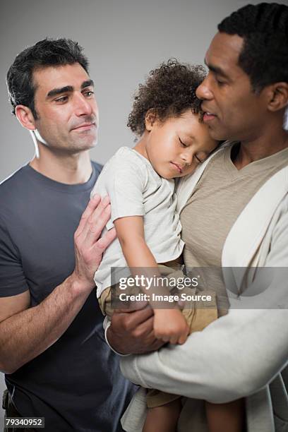 men with sleepy child - gay person color background stock pictures, royalty-free photos & images