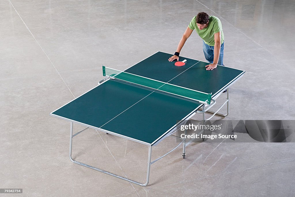 Young man leaning on a table tennis table