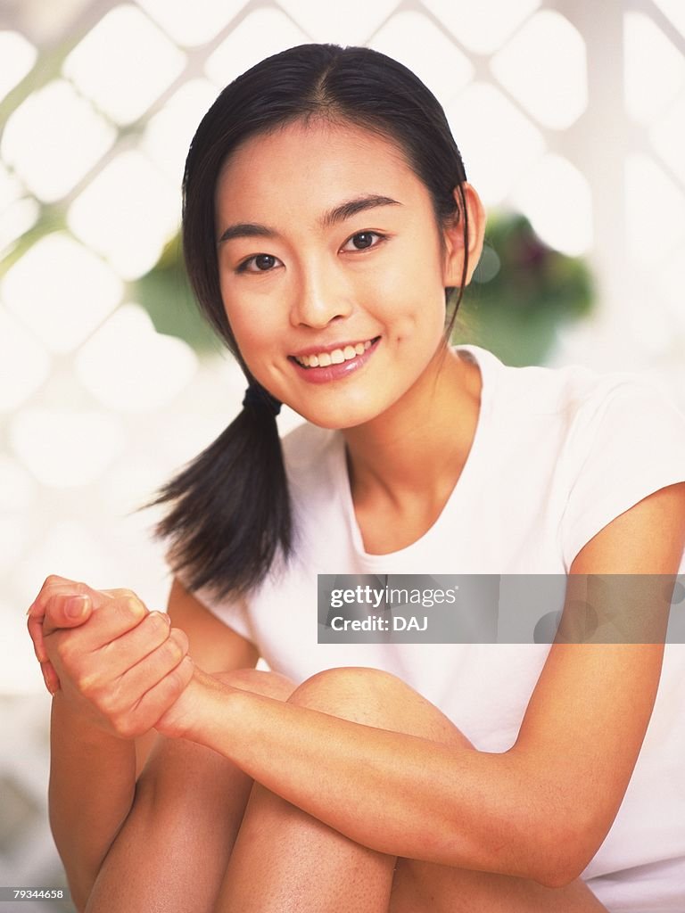 Woman folding hands and clutching her knees to chest, smiling